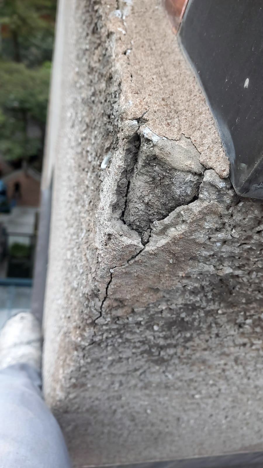 Desplacamento de concreto em borda de platibanda, com cavidade expondo o agregado