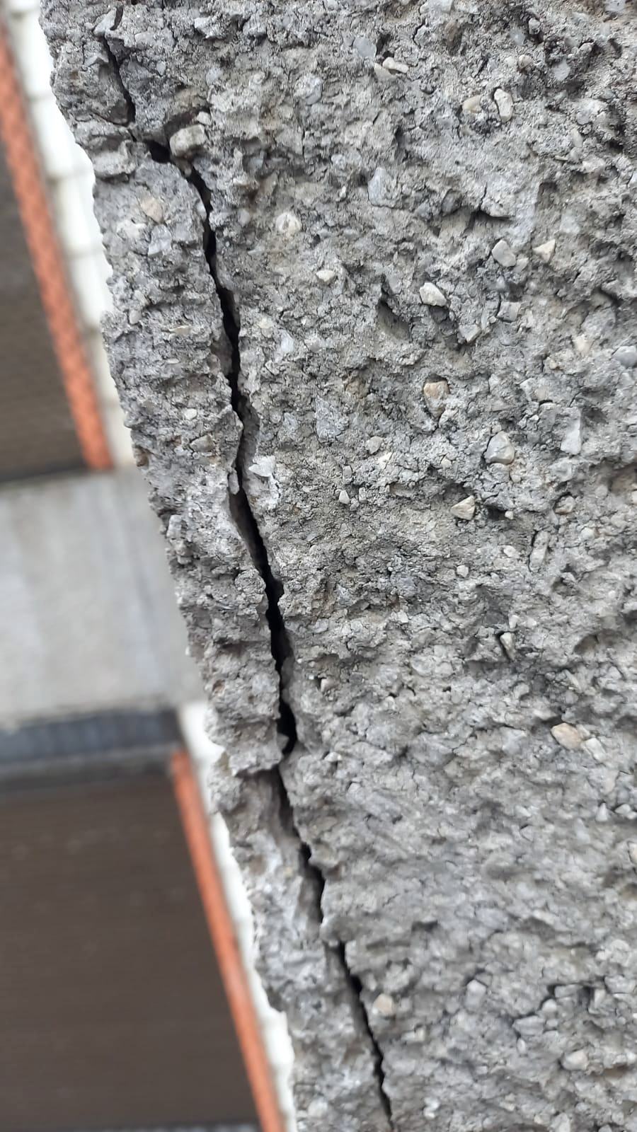 Fissura vertical em concreto aparente no encontro com revestimento cerâmico de fachada