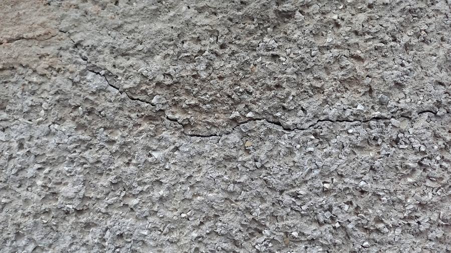 Fissura horizontal percorrendo superfície de concreto com agregado exposto