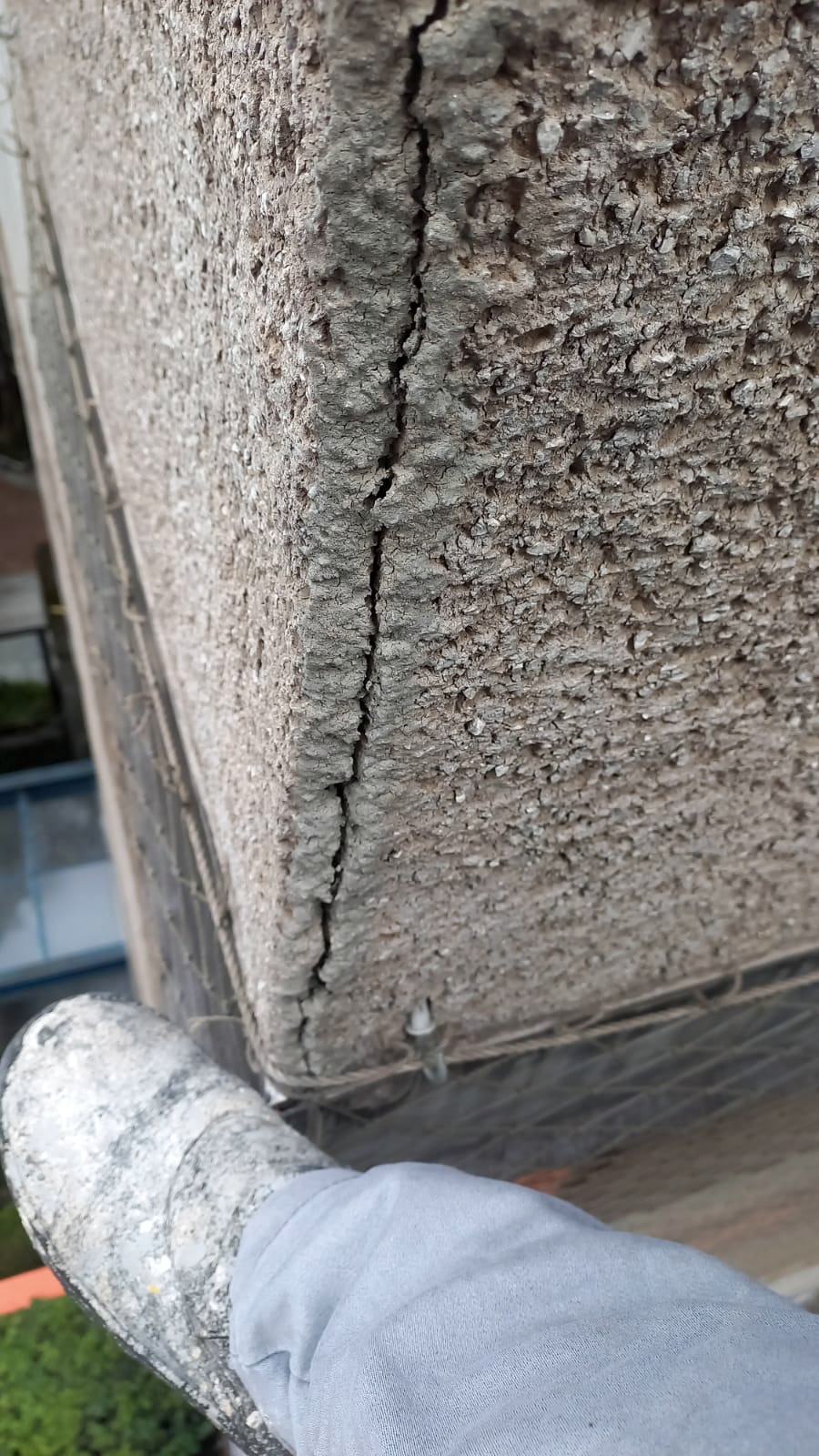 Fissura vertical em quina de pilar de concreto, com referência de escala