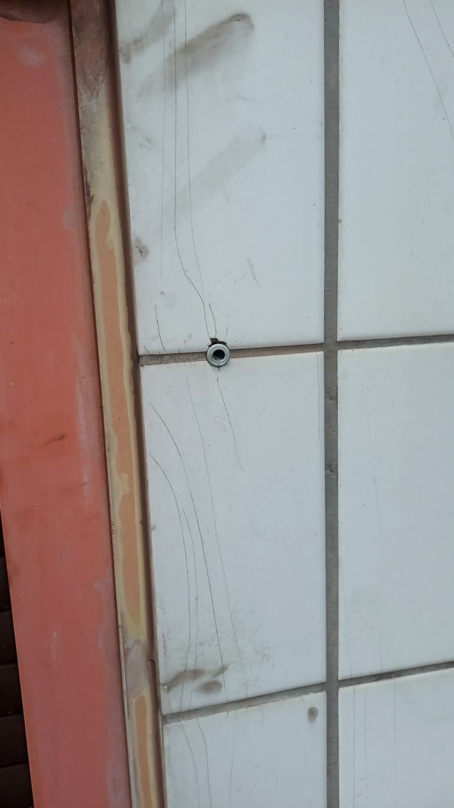 Fissuras finas irradiando de ponto de fixação em revestimento cerâmico de fachada