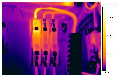 Termograma em falsa cor de um disjuntor multipolar em painel elétrico, com o aquecimento concentrado no terminal superior de um dos polos. Escala do instrumento de 51,2 °C a 85,1 °C.